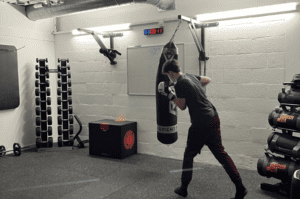 Image: boy in black tracksuit boxing punch bag