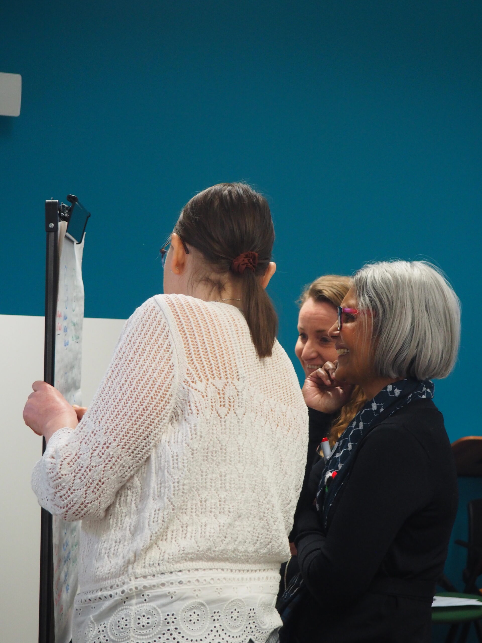 Two workshop participants standing at a flipchart, reviewing notes and discussing ideas together.