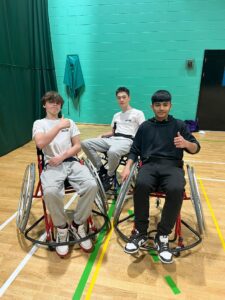 Three young people participating in wheelchair sport activities, posing with thumbs up
