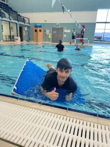 Leisure careers: Young person in pool on a foam board with thumbs up